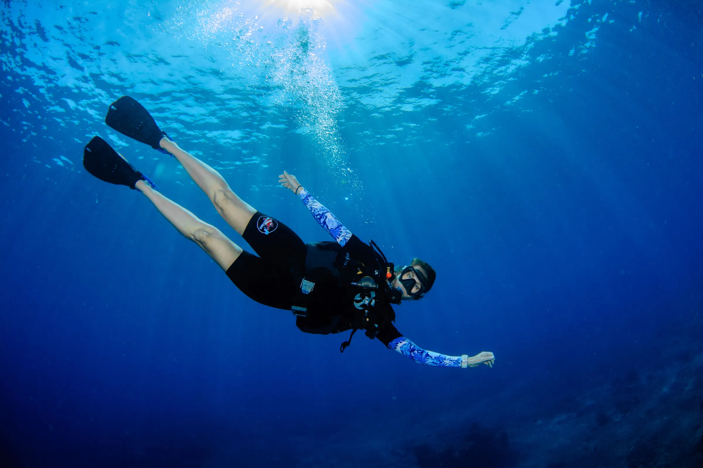 Diver swimming up through blue